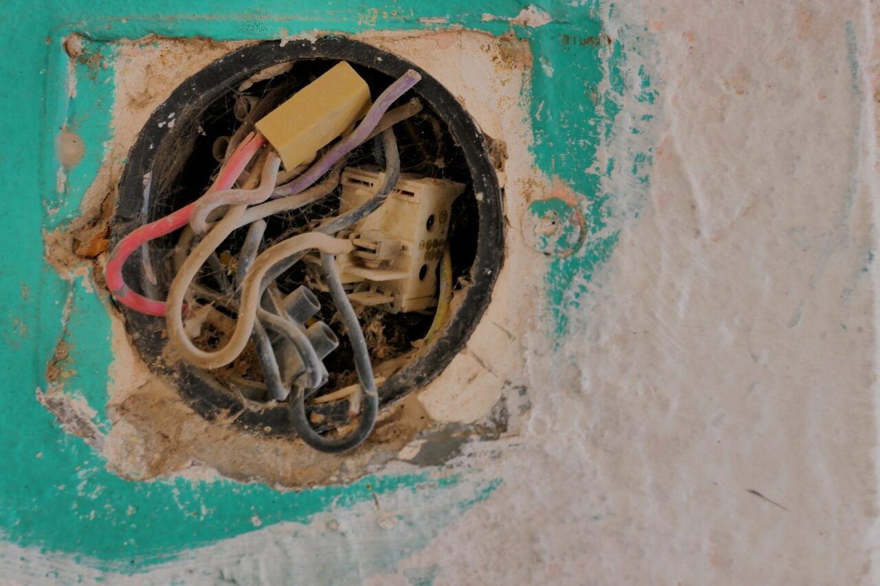 Anciens fils électriques dénudés visibles dans un mur avant des travaux d’isolation.