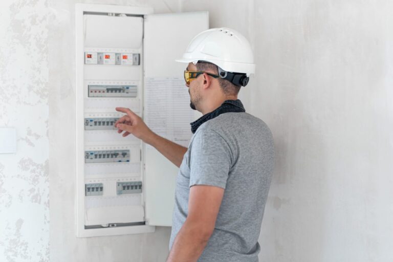 Électricien vérifiant le tableau électrique avant l’installation d’une pompe à chaleur.