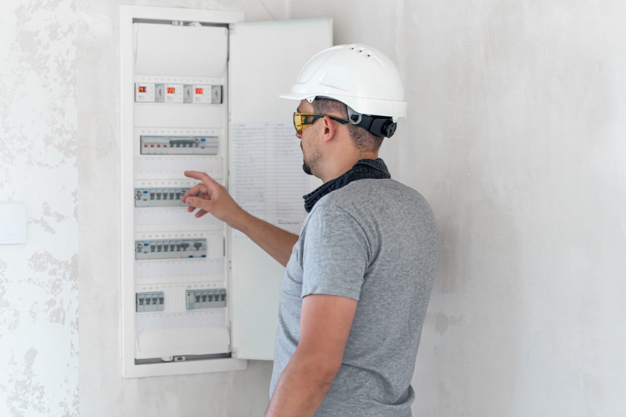 Électricien vérifiant le tableau électrique avant l’installation d’une pompe à chaleur.