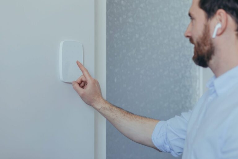 Locataire installant une alarme sans fil avec une fixation adhésive, sans percer le mur.