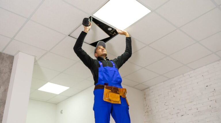 Un artisan pose des panneaux acoustiques sur une cloison mitoyenne dans une chambre.