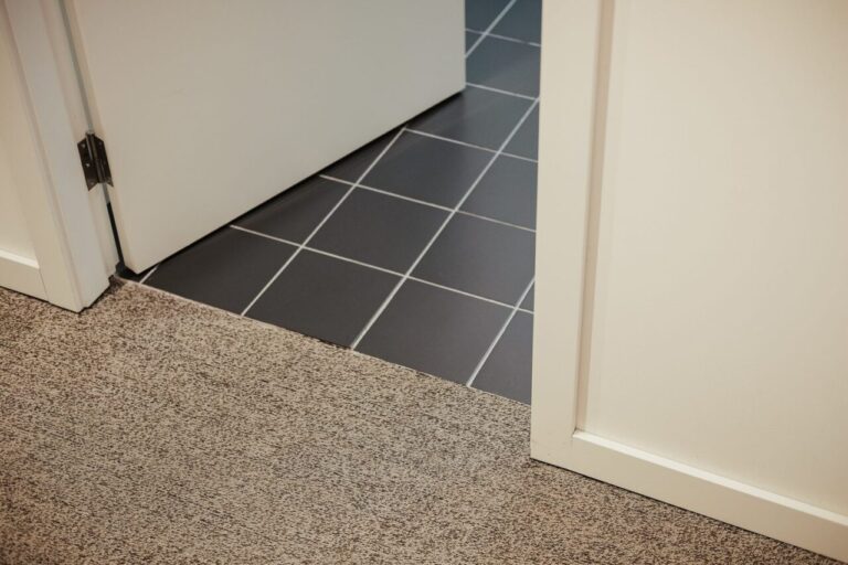 Pose d’un nouveau sol par-dessus un carrelage existant, au niveau d’une porte.