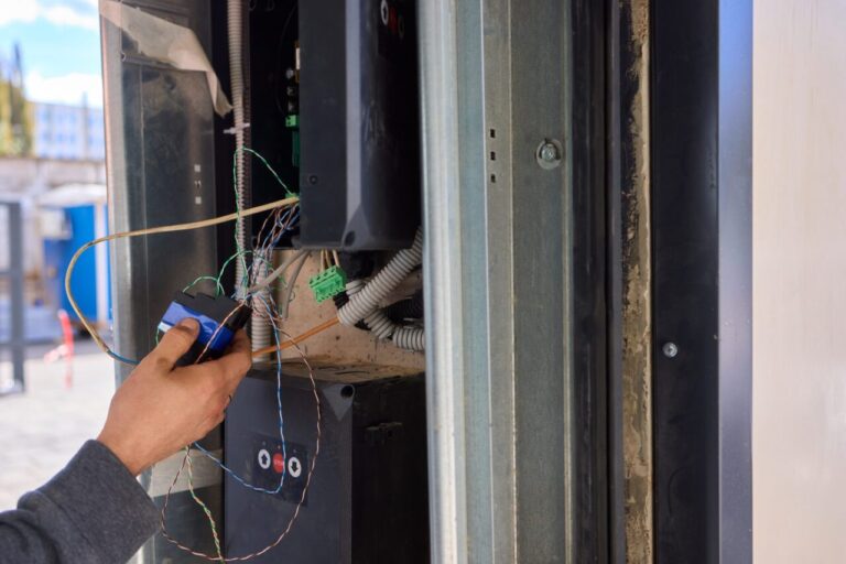 Électricien faisant passer le câble d’un visiophone près d’une porte d’entrée en rénovation.