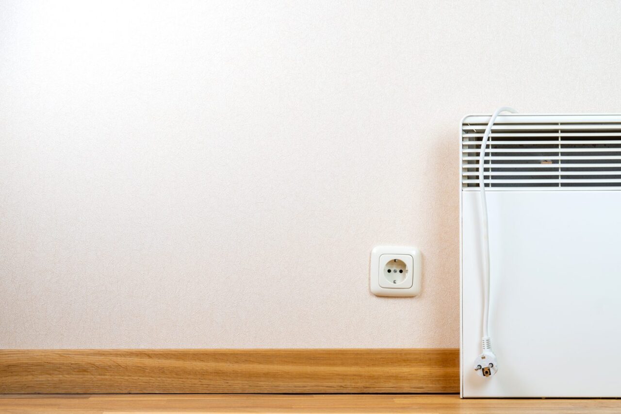 Radiateur d’appoint branché sur une prise électrique murale qui chauffe.