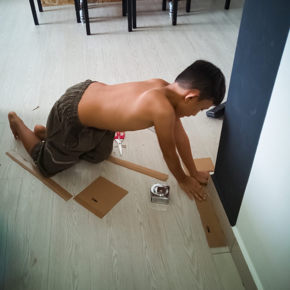 Main soulevant délicatement un carreau de carrelage qui se décolle dans une entrée.